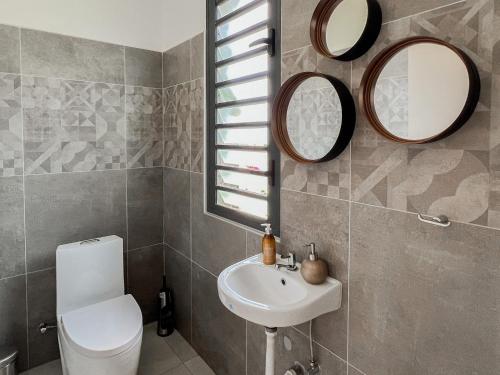 a bathroom with a toilet and a sink and mirrors at Résidence Celestial - Premium 3 bedrooms Villa with volcanic stone Pool in Grand Baie