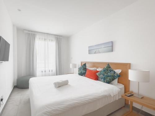 a white bedroom with a large white bed with colorful pillows at Résidence Celestial - Premium 3 bedrooms Villa with volcanic stone Pool in Grand Baie