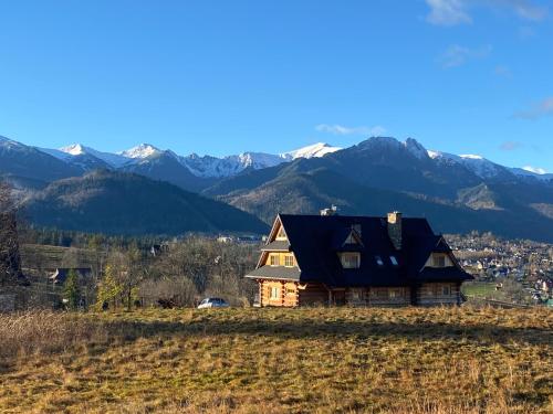 a house on a hill with mountains in the background at SOPA Zakopane in Zakopane