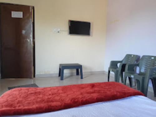 een kamer met stoelen en een bed met een rode deken bij Two Brother's Hotel lodging And Restaurant WARDHA in Wardha