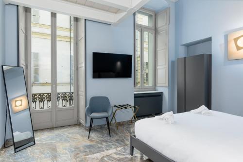 a bedroom with a bed and a chair and a tv at Q71 TIMELESS SUITES in Turin