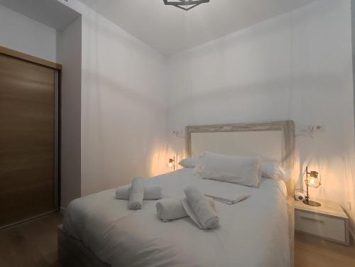 1 dormitorio con cama blanca y almohadas blancas en Ohana home 1 en Málaga