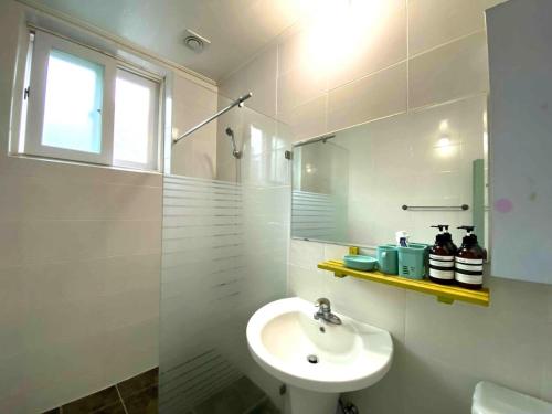 a white bathroom with a sink and a shower at Smile Resort in Sokcho