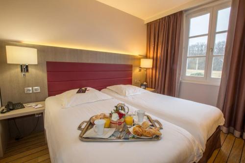 une chambre d'hôtel avec un plateau de nourriture sur un lit dans l'établissement Logis Hôtel Les Tuileries, à Féy