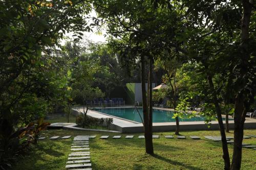 a swimming pool in the middle of a yard with trees at Hotel Ro Kalawewa - Anuradhapura District in Kalawewa Walauwa