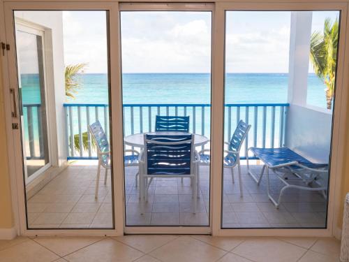 balcón con mesa, sillas y vistas al océano en Deluxe Ocean View Villas - Just Steps From White Sand Beaches en Creek Village