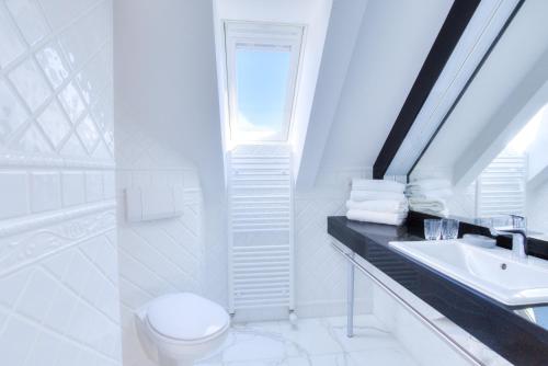 a white bathroom with a toilet and a sink at Windeby 6D in Wenningstedt