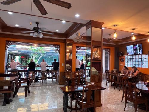 巴東海灘的住宿－Nanai 2 Residence Patong Phuket，一间设有桌子的餐厅,有坐在桌子上的人