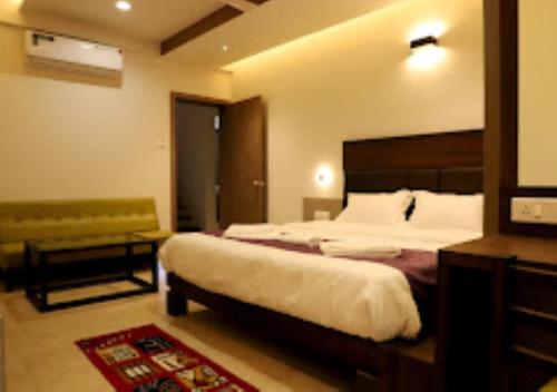 a hotel room with a large bed and a bench at LOTUS LODGE Kalmath in Kankauli