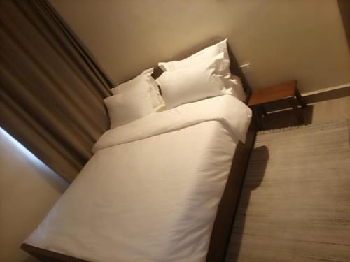 a small bed with white sheets and pillows at Lux Suites Narok Holiday Homes in Narok