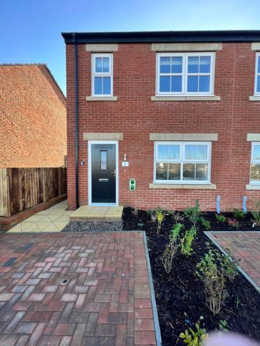 a brick house with a brick driveway at Luxury 3 bedroom house on the outskirts of Newcastle near to Hadrians Wall in Newcastle upon Tyne