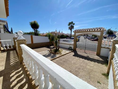 una valla blanca con una puerta y palmeras en La Fonda de Julia Magnifica casa muy luminosa y amplia con chimenea y barbacoa, en Matalascañas
