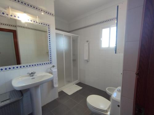 a bathroom with a sink and a toilet and a mirror at La Fonda de Julia Magnifica casa muy luminosa y amplia con chimenea y barbacoa in Matalascañas