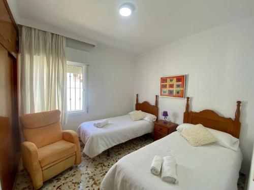 a hotel room with two beds and a chair at La Fonda de Julia Magnifica casa muy luminosa y amplia con chimenea y barbacoa in Matalascañas