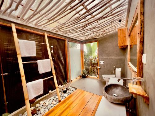 uma casa de banho com um lavatório e um WC num quarto em Manulalu Jungle em Bajawa