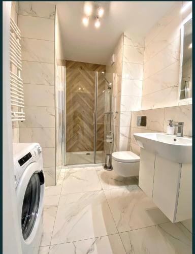 a bathroom with a washing machine and a sink at Apartamenty Fuzja - Komfortowe Mieszkania Blisko Centrum Łodzi Garaż in Łódź