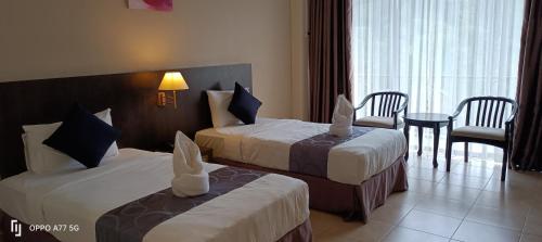 a hotel room with two beds and a table and chairs at Amverton Heritage Resort in Melaka