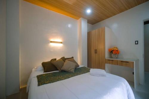 een slaapkamer met een groot wit bed met kussens bij Entire place with pool and bar16pax accomdtn in Bacolod