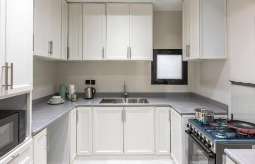 شقة غرفتين وصالة ومطبخ في المدينة المنورة: مطبخ أبيض مع دواليب بيضاء ومغسلة