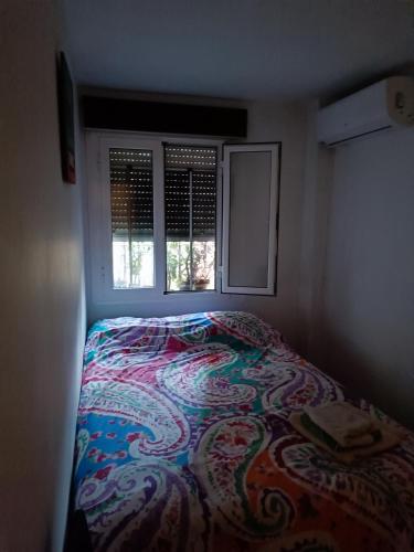 a bed in a small room with a window at Alojamiento turístico MN in Seville