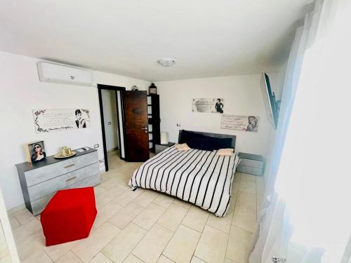 a bedroom with a striped bed and a red stool at Incredibile Appartamento con doccia Idromassaggio 