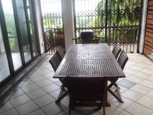 a wooden table and chairs on a porch with windows at Marina Beach Guest house in Southbroom