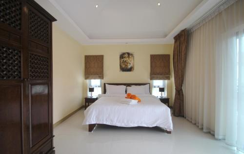 a bedroom with a large white bed with an orange pillow on it at Talay Sawan Pool Villa 27-12 in Bang Sare