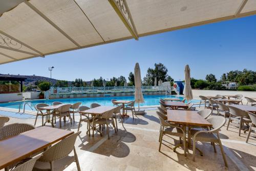 a patio with tables and chairs next to a pool at Smart Stay Beach Bodrum -All Inclusive in Gümbet
