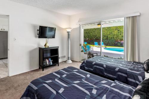 a bedroom with a bed and a flat screen tv at Chi Chi House in Palm Springs