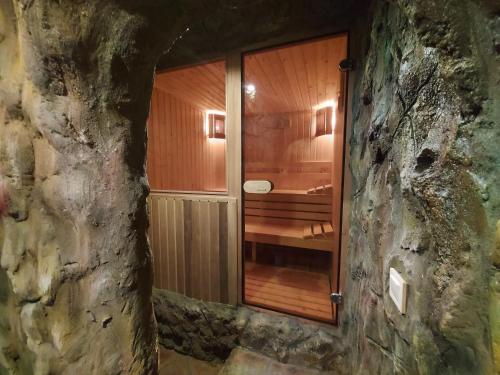 y baño con ducha de madera en una pared de piedra. en Самостоятелна Вила в Хаджи Марковата къща за гости в Дряново en Dryanovo