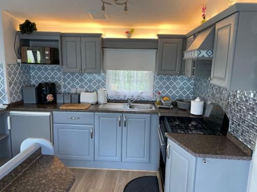 a kitchen with blue cabinets and a sink at Haven caravan park Cala gran in Fleetwood