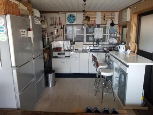 a kitchen with a refrigerator and some chairs in it at Guesthouse En in Ochi