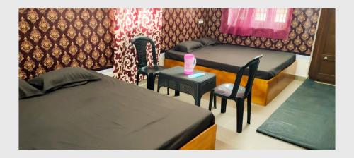 TirunallārにあるTHIRUNALLAR S A RESIDENCYのベッド2台、テーブル、椅子が備わる客室です。