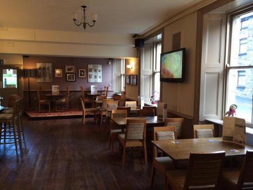 a dining room with tables and chairs and a tv at Markets Tavern Hotel in Brecon