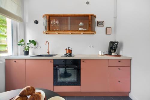eine Küche mit rosa Schränken und einem Waschbecken in der Unterkunft Apartament Szamotulska 59A in Posen