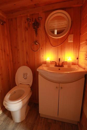 a bathroom with a toilet and a sink with candles at Waterfront Tiny House near Pomquet Beach in Antigonish