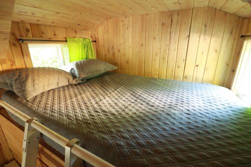 a bed in a wood paneled room in a trailer at Waterfront Tiny House near Pomquet Beach in Antigonish