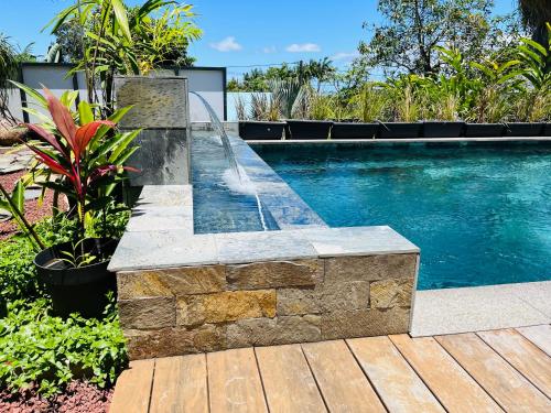 a swimming pool with a water fountain in a yard at Le Clos d'Isis - Piscine chauffée in Le Tampon