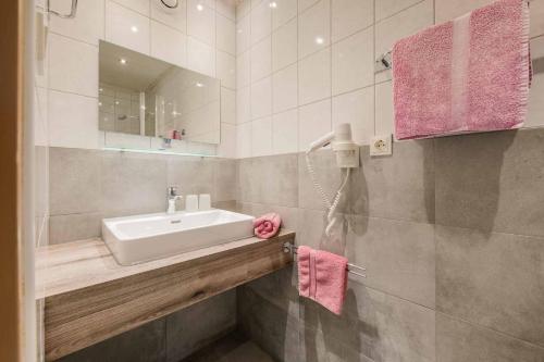 a bathroom with a sink and a mirror and pink towels at Haus Waltraud in Neustift im Stubaital