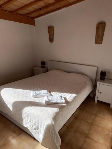 une chambre avec un lit blanc avec deux serviettes dessus dans l'établissement Typique maison de village, à Saint-Quentin-la-Poterie