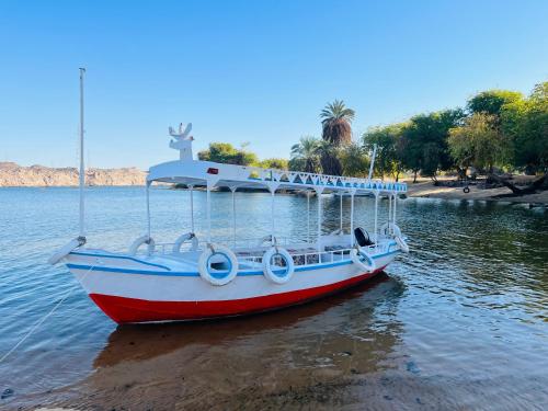 un barco rojo y blanco sentado en el agua en Wanas Kato Guest House, en Shellal