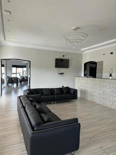 a living room with a black leather couch in a room at Kacoke Madit Hotel and Cultural Centre, Gulu in Gulu