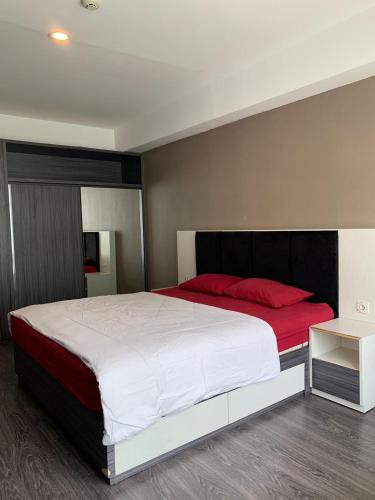 - une chambre avec un grand lit blanc et des oreillers rouges dans l'établissement Vins Room at Mataram City Tower Sadewa, à Kejayan