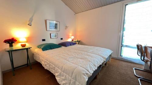 ein Schlafzimmer mit einem großen Bett und einem Fenster in der Unterkunft Jolie maison avec jardin, piscine et parking in Sainte-Marie-de-Ré