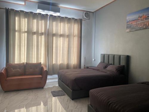 a bedroom with two beds and a chair and a window at Tulip Hotel in Louang Namtha