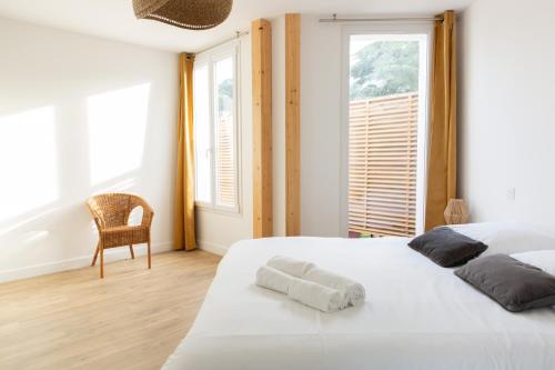 une chambre avec un grand lit blanc et une chaise dans l'établissement Appartement - Le Miln, à Carnac
