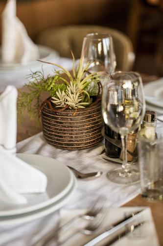 a table with plates and glasses and a potted plant at Hotel & Restaurant Ponte Bianco in Vranje