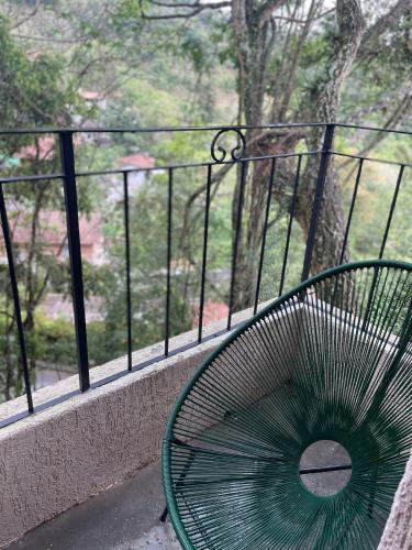 a green bench sitting on a balcony with a view at VILLA ITÁLIA CHALÉ in Santo Antônio do Pinhal