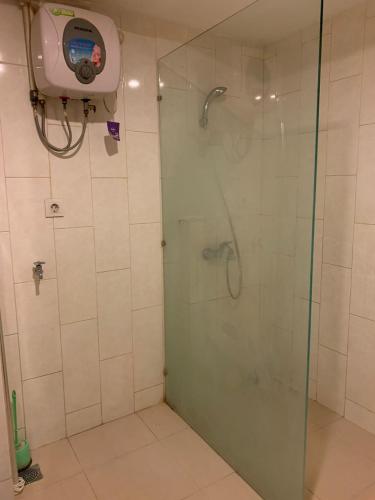 La salle de bains est pourvue d'une douche avec une porte en verre. dans l'établissement Vins Room at Mataram City Tower Sadewa, à Kejayan