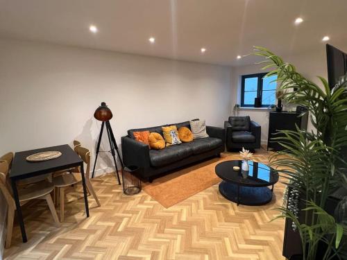 een woonkamer met een zwarte bank en een tafel bij The Orchard - Ground Floor Flat in Bristol